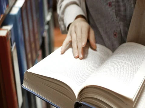Young woman reading book in library or book store Stock Footage