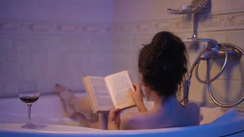Young woman reading a book while relaxing in the bathtub Stock Footage 333567085