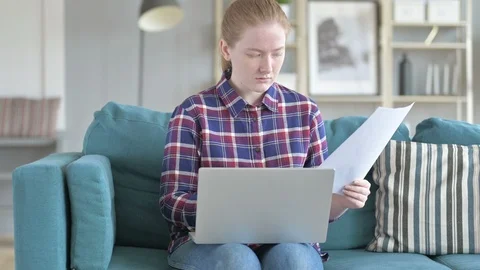 Young Woman reading Documents While Sitting on Couch Stock Footage 114787912
