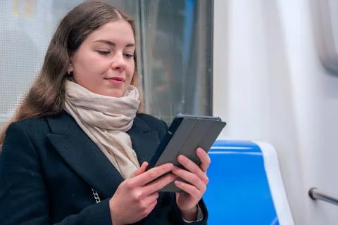 Young Woman Reading on E-Reader While Commuting on Subway Train Stock Photos