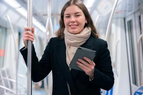 Young Woman Reading on E-Reader While Commuting on Subway looking at camera Stock-Fotos