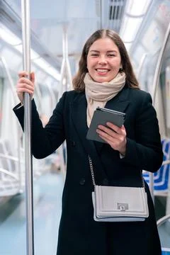 Young Woman Reading on E-Reader While Commuting on Subway looking at camera Stock-Fotos