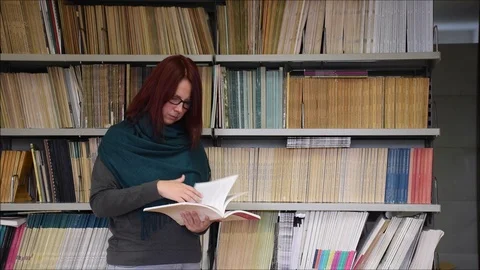 Young woman reading in the library Stock Footage 106627798