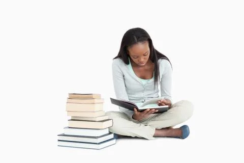 Young woman reading next to a stack of books 写真素材