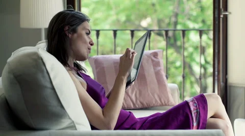 Young woman reading a tablet on sofa at home HD Stock Footage 44794136