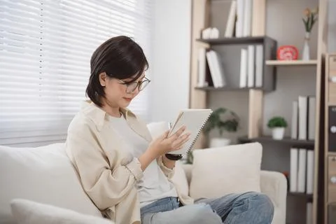 Young Woman Reading Tablet While Sitting on Couch in Modern Living Room wit.. Stock Photos