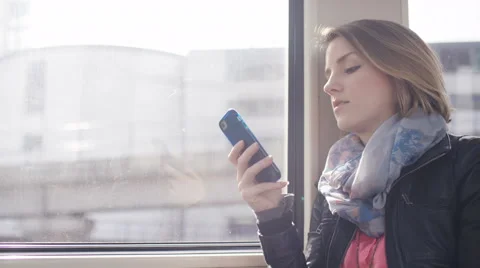 Young woman reading through her phone whilst on a train journey, in slow motion Stock Footage