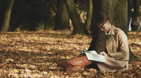 Young woman reads under a tree. Autumn, fall foliage. Stock Footage 42820132