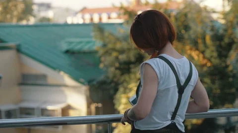 Young woman red hair holding and using mobile phone back view Stock Footage