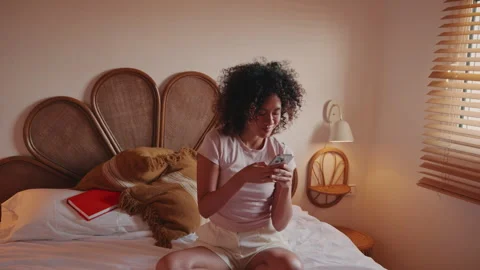 Young Woman Relaxing in Bed Using Smartphone Stock Footage 332684149