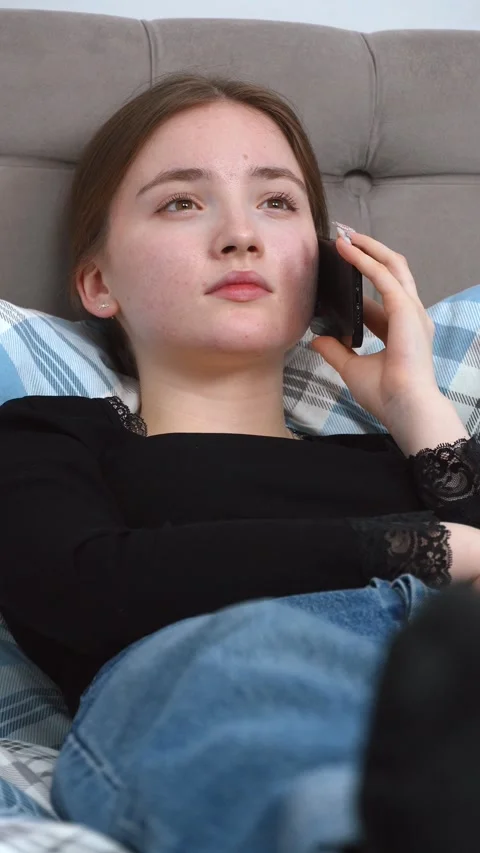 Young woman relaxing on bed while talking on phone Vidéo 309772689