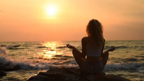 Young woman relaxing by practicing yoga on the beach near calm sea, lotus Stock Footage