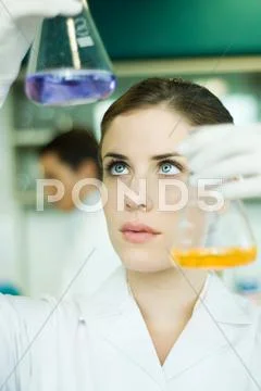 Young Woman In Research Lab, Holding Up Two Flasks