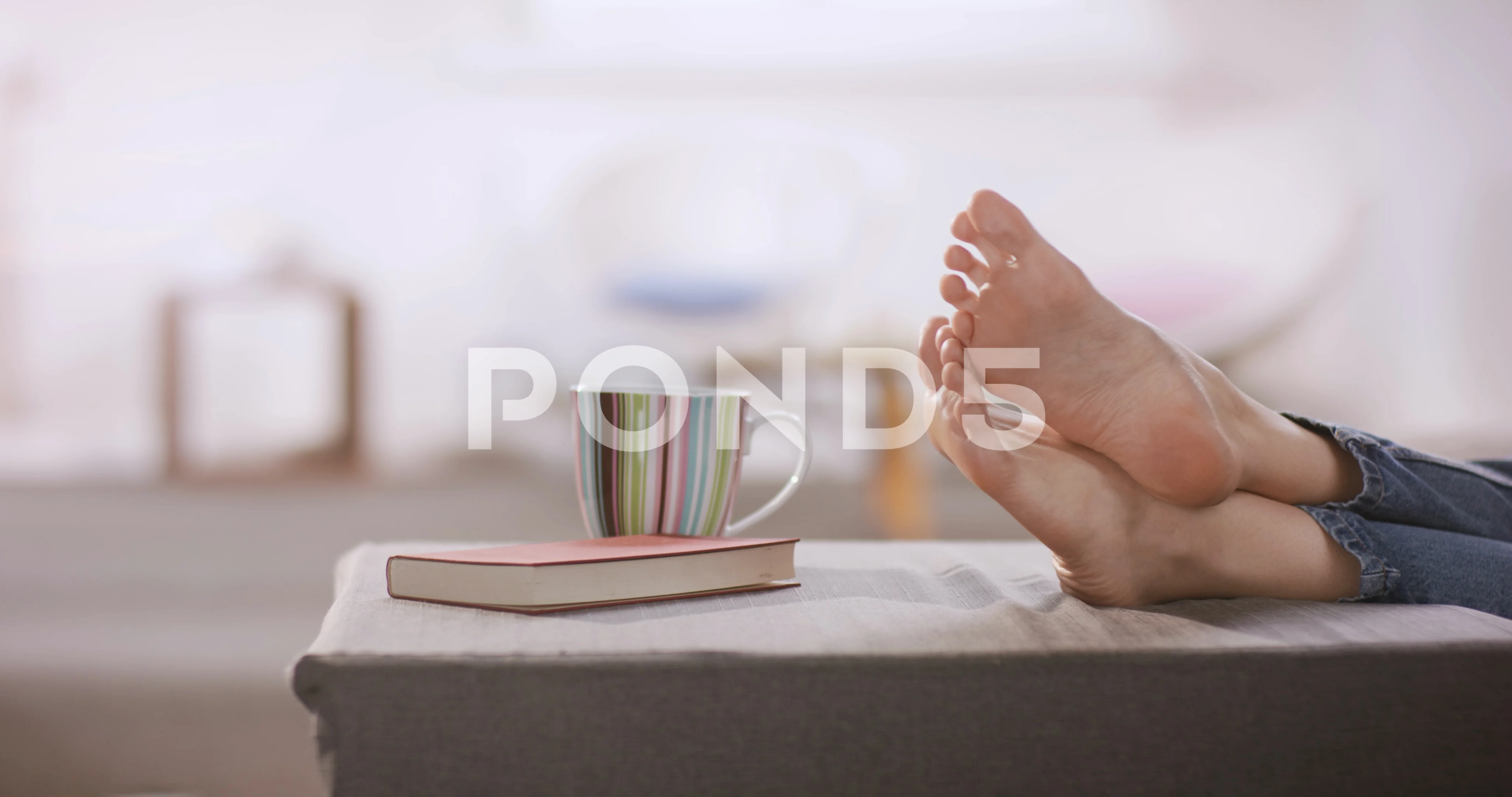 Young woman resting her bare feet on grey couch