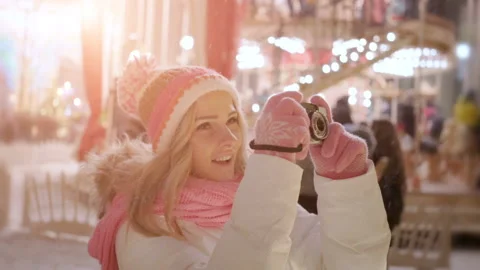 Young woman with retro camera at christmas market in snow winter evening Stock Footage 100431153