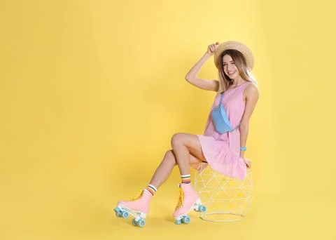 Young woman with retro roller skates on color background, space for text Stock Photos
