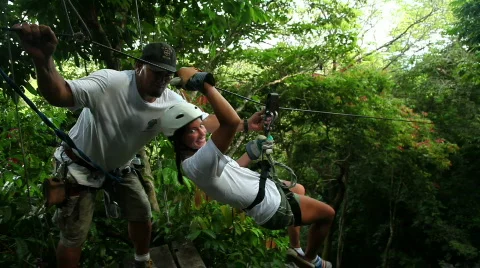 Young woman riding a zipline on a canopy tour Stock Footage