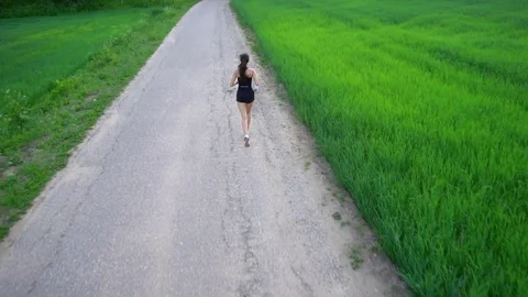 Young woman runner is running down the road in a sporty uniform Stock Footage 77628498