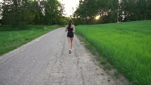 Young woman runner is running down the road in a sporty uniform Stock Footage 77628959