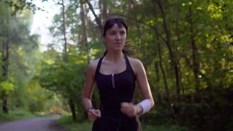 Young woman runner is running down the road in a sporty uniform Stock Footage 77629076