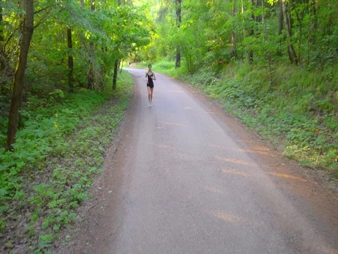 Young woman runner is running down the road in a sporty uniform Stock Footage 77629257