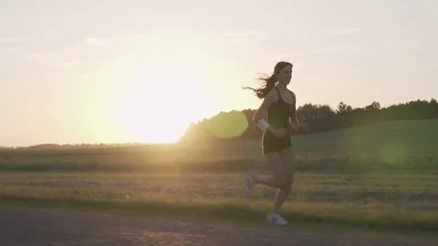 Young woman runner is running down the road in a sporty uniform Stock Footage 77698245