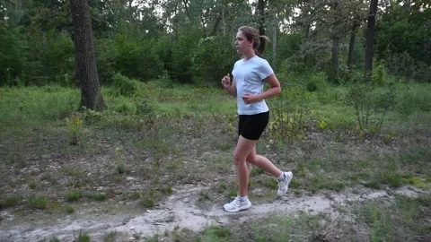 Young woman running along dirt park pathway in slow motion. Stock Footage 329516341