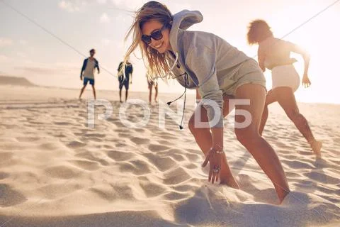 Young Woman Running Race With Friends At The Beach