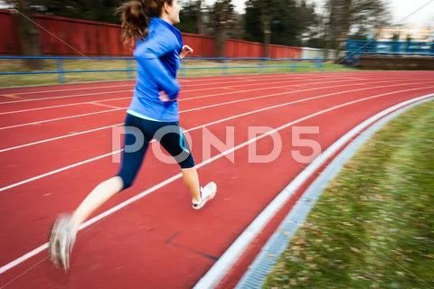 Young woman running at a track and field stadium Stock Photos
