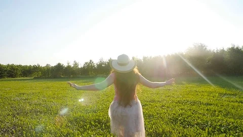 A young woman runs along a green glade at sunset Stock Footage
