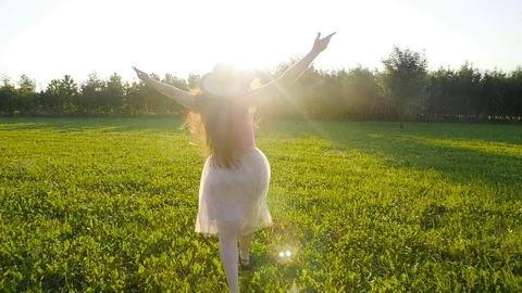 A young woman runs along a green glade at sunset Stock Footage