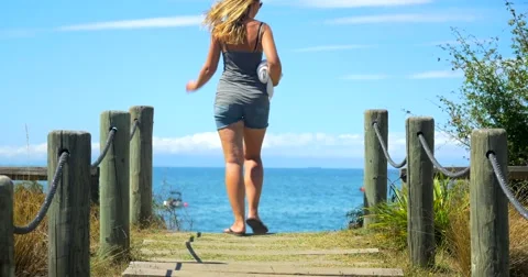 Young woman runs towards gorgeous beach with blue sky 動画素材 59807498