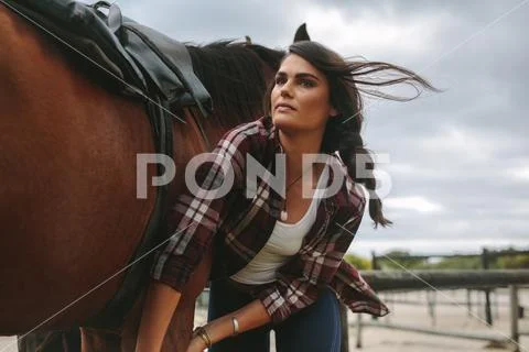 Young woman saddling the horse Stock Photos