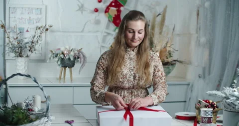 A young woman salesman in a flower shop packs a Christmas wreath in a box. Gift Stock Footage