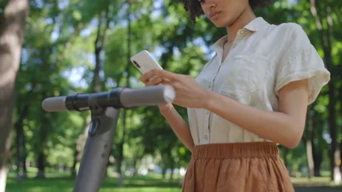 Young woman scanning qr code on e-scooter to pay for rent, checking ride time Stock Footage