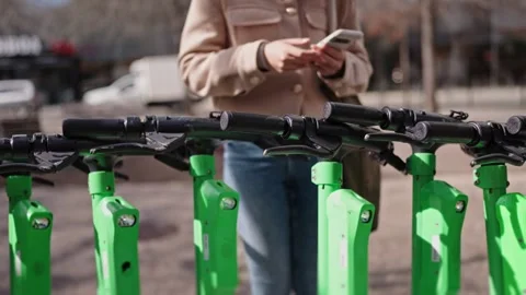 Young Woman Scanning QR Code for Electric Scooter Rental Stock Footage 275856345