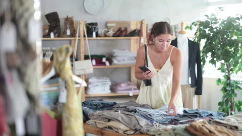Young woman scanning qr code of trousers in clothing store Stock Footage 318437712