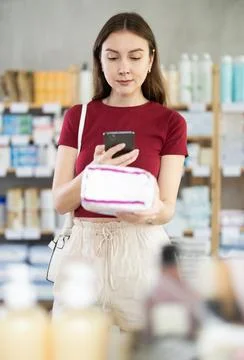 Young woman scanning QR-code on feminine pads in drugstore Stock Photos