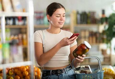 Young woman scanning qr code of pickled tomatoes with cucumbers Foto stock