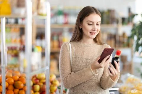 Young woman scanning qr code of soy sauce Stock-Fotos