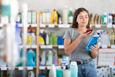 Young woman scanning qr code for cleaning spray Stock-Fotos