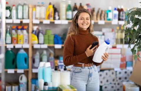 Young woman scanning QR-code on detergent in supermarket Stock Photos