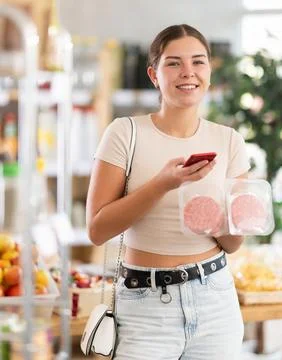 Young woman scanning qr code of raw hamburger Fotos de archivo