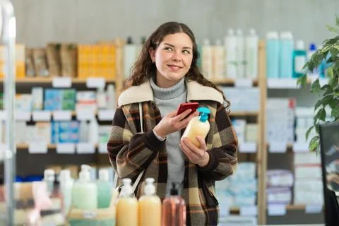 Young woman scanning qr code of hand soap Fotos de archivo