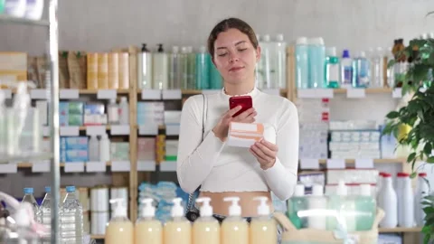 Young woman scans the barcode of a package with pills and medicines on her 動画素材 341379761