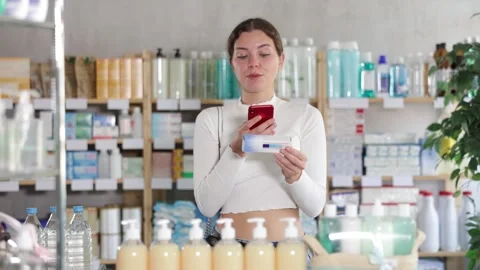 Young woman scans the barcode of a package with medical ointment through the Stock Footage 341783538