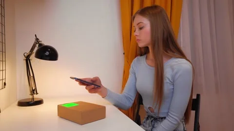 Young woman scans the QR code with a mobile phone on the parcel she received Stock Footage 181476720