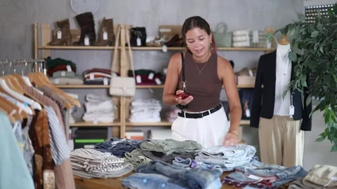 Young woman scans a QR code and a tag on jeans on mobile phone, she reads the Video stock 317987604