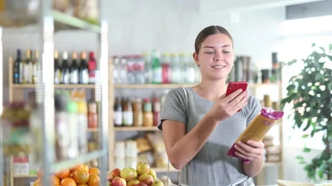 Young woman scans the QR code of a spaghetti package on an online application on Stock Footage 326308441