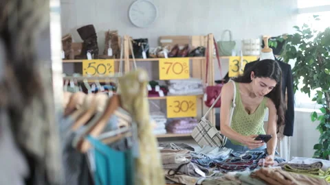 Young woman scans QR code and label of trousers or pants using mobile phone Stock Footage 327139055